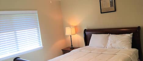 A neatly made bed with a wooden headboard, a bedside lamp, and a ceiling fan.