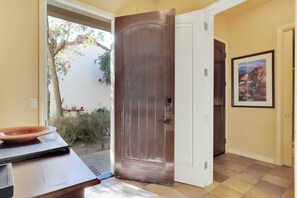 A hallway with a wooden door, a framed picture on the wall, and a table with a bowl.