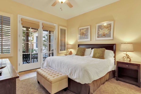 A bedroom with a large bed, a bench, a nightstand, and two wall-mounted lamps.