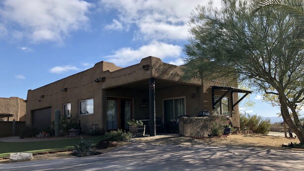 Una casa intonacata con patio coperto, garage e un cactus nel giardino.