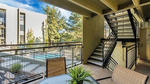 Un balcon donnant sur une piscine, un escalier et une table avec des chaises.