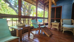 Une terrasse en bois avec une table, des chaises et un fauteuil en osier.