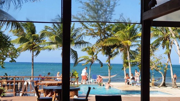 Un espace piscine situé au bord de la plage, avec des terrasses en bois et une vue sur l’océan.