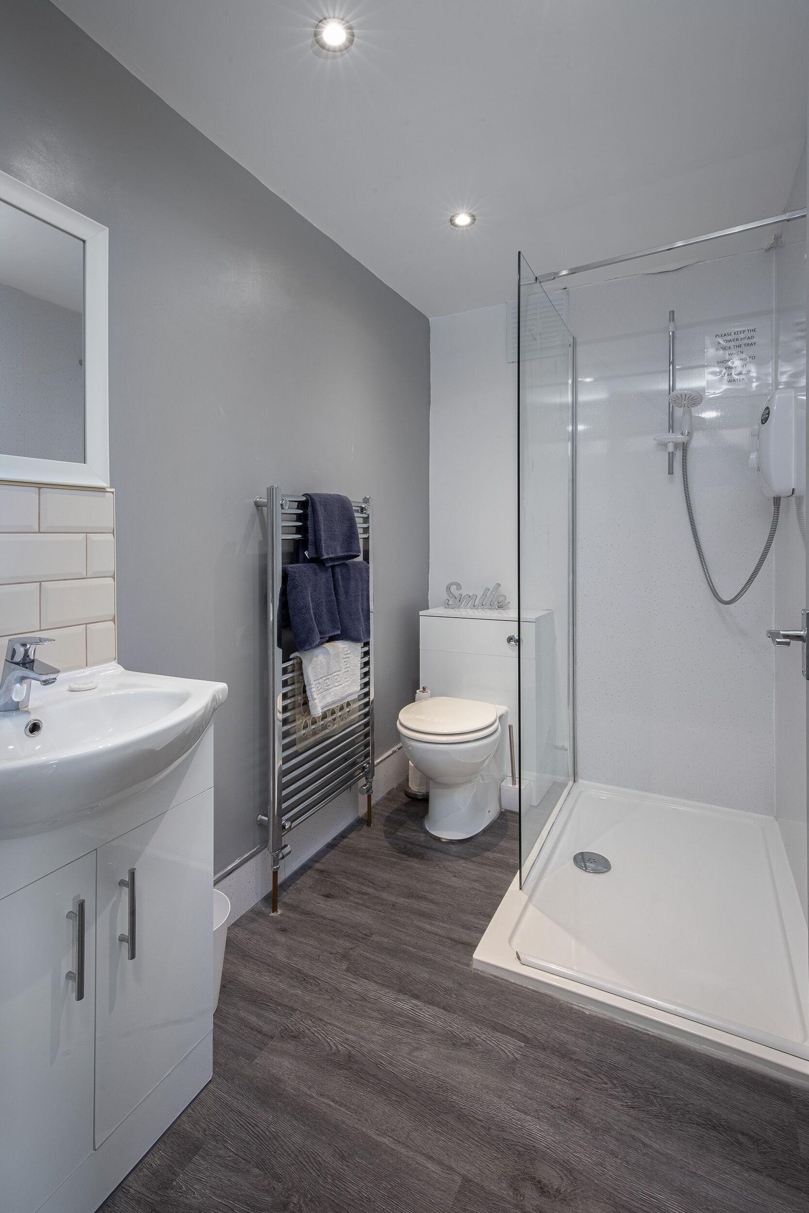 Een moderne badkamer met een douchecabine van glas, een witte wastafel en een toilet.