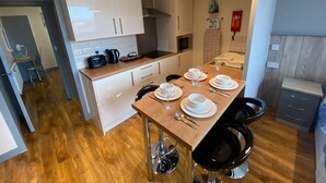Eine moderne Küche mit weißen Schränken, einer Holztischplatte und einem Essbereich mit Tisch für vier Personen.