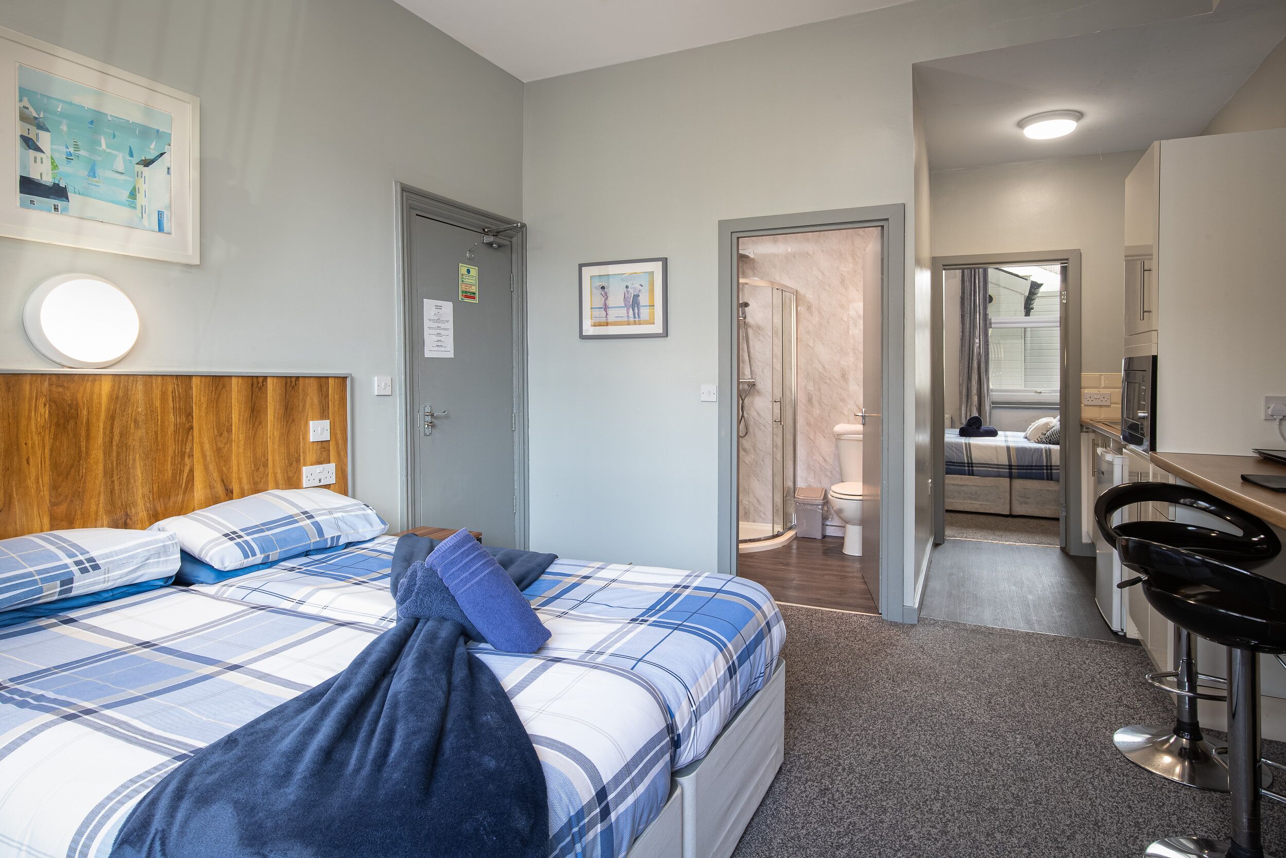 Hotellihuone, jossa on sänky, työpöytä ja suihkutila.