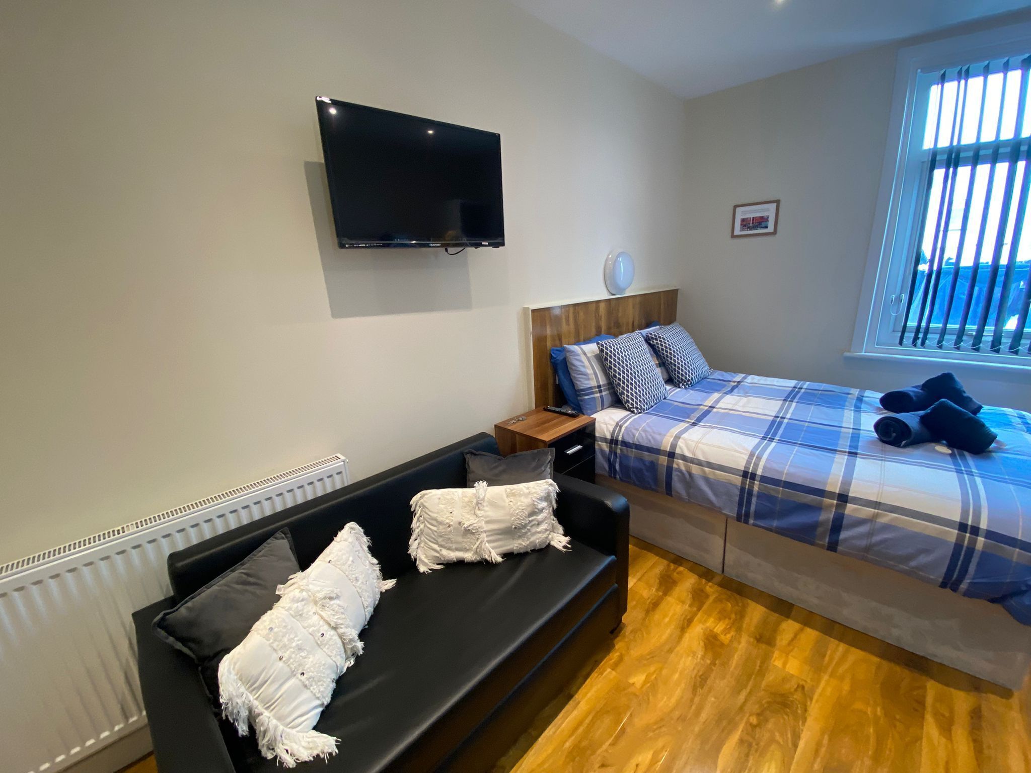 Una camera con un letto, una TV, una finestra e un divano.