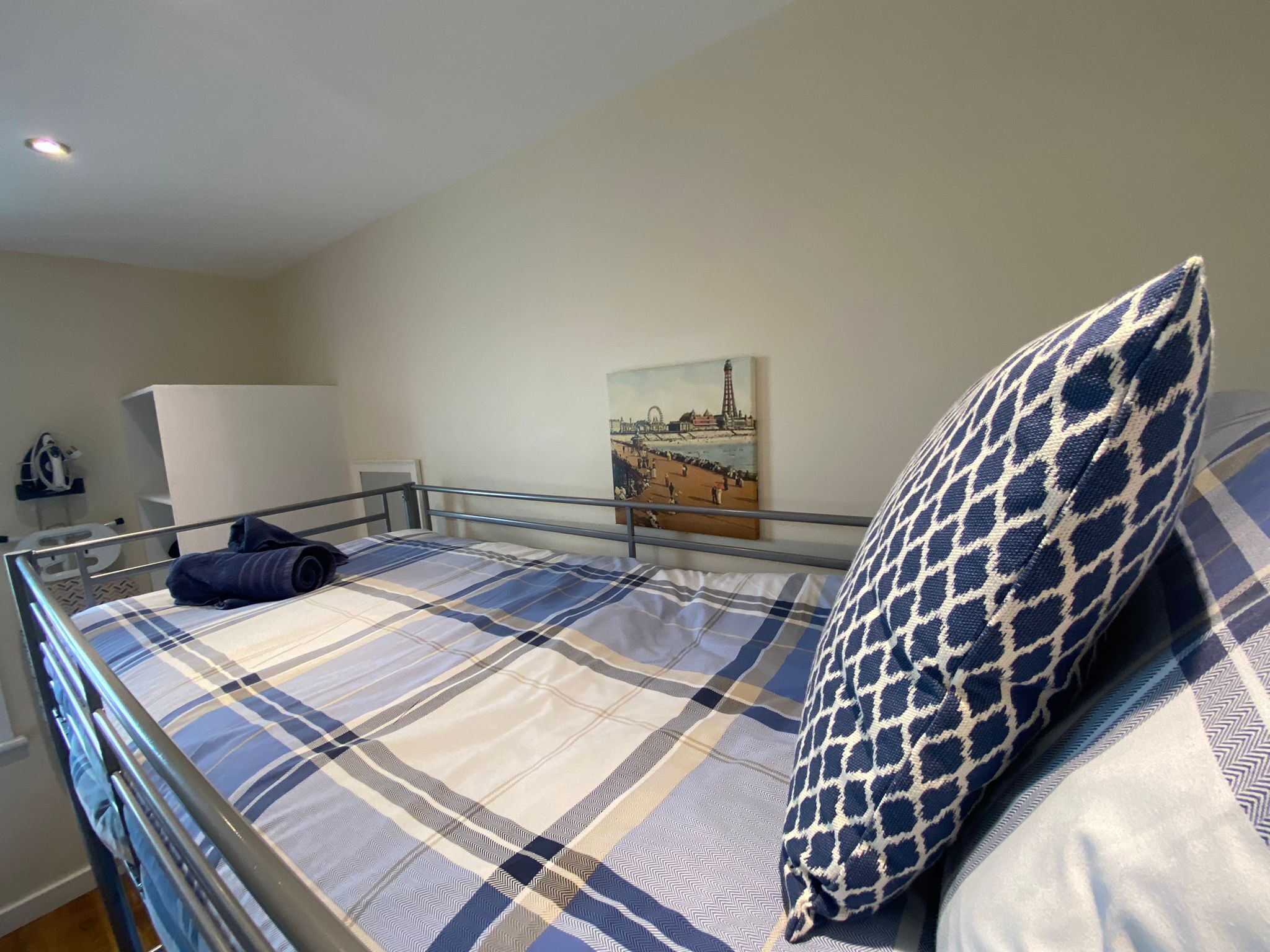 Une chambre à coucher avec un lit, un oreiller, un tableau accroché au mur et une armoire blanche.