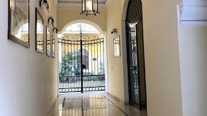 A hallway with a polished marble floor, a black wrought iron gate, and a ceiling light fixture. - Gracchi Guest House (Rome)