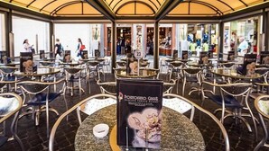 A restaurant with round tables and chairs, a poster on the table, and a glass wall in the background. - Gracchi Guest House (Rome)