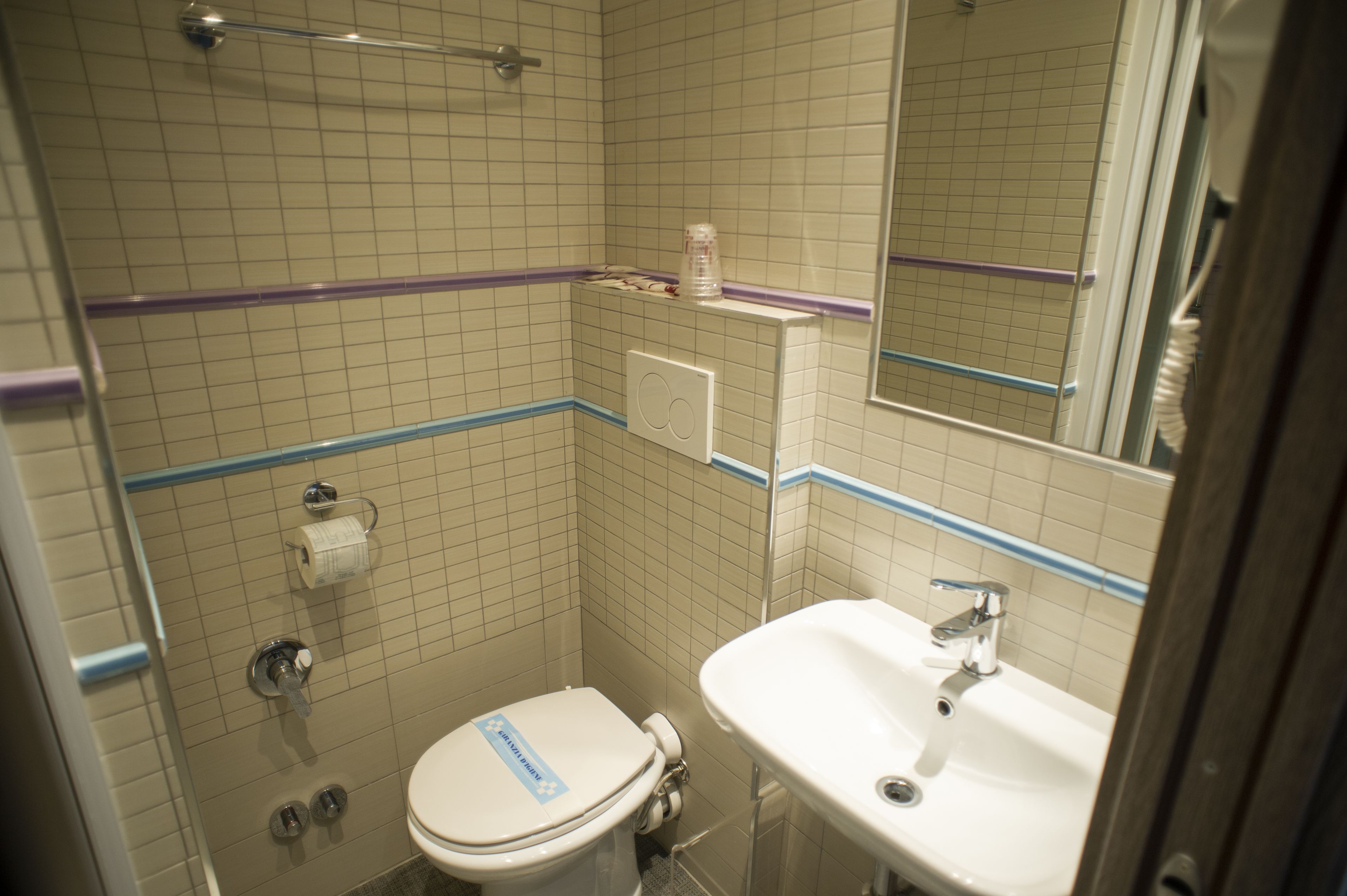 Un baño pequeño con inodoro, lavamanos y espejo.