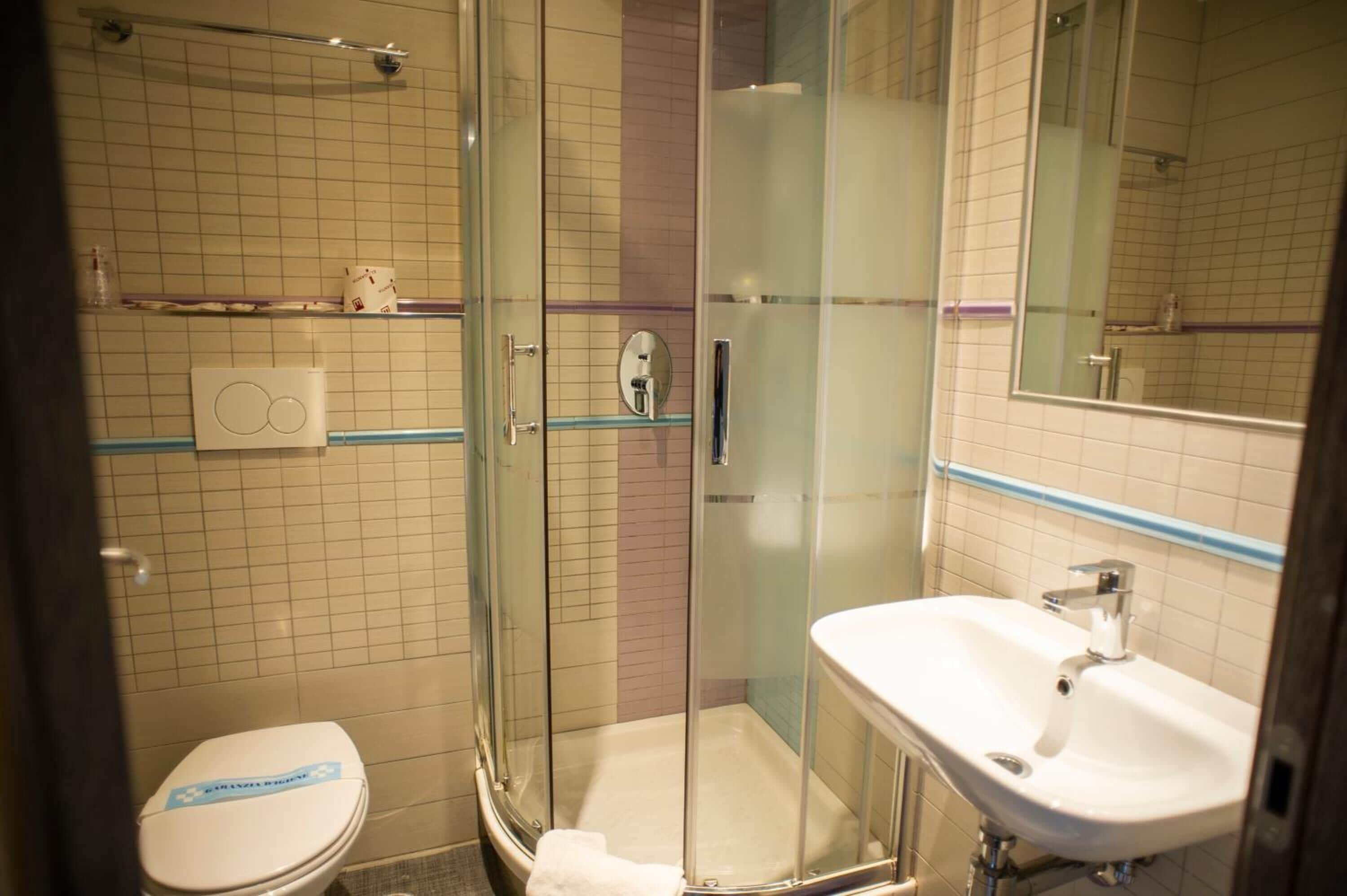 A bathroom with a glass-enclosed shower, a white sink, and a toilet.