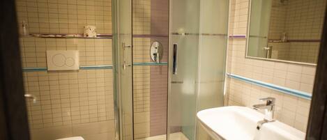 A bathroom with a glass-enclosed shower, a white sink, and a toilet.
