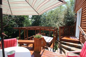 A wooden deck with a hot tub, a table, and a chair.