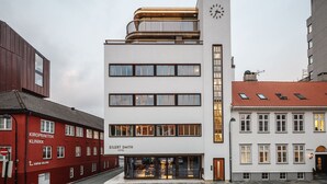 Un hotel moderno con una torre de reloj, varios pisos y una entrada visible.
