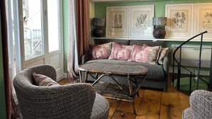 Uma sala de estar aconchegante com sofá, duas poltronas, uma mesinha redonda e uma escada.