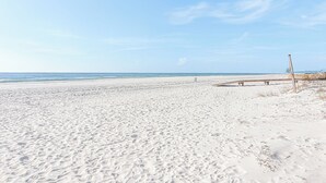 A wide sandy beach with a clear sky and calm sea. - Unique Beach Cottage with pool and easy beach access (Gulf Shores)
