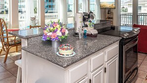 A kitchen with a granite countertop, a cake, and a vase of flowers. - Unique Beach Cottage with pool and easy beach access (Gulf Shores)
