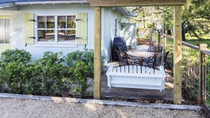 Ein Haus mit Veranda, Tisch und Stühlen sowie einem weißen Zaun.