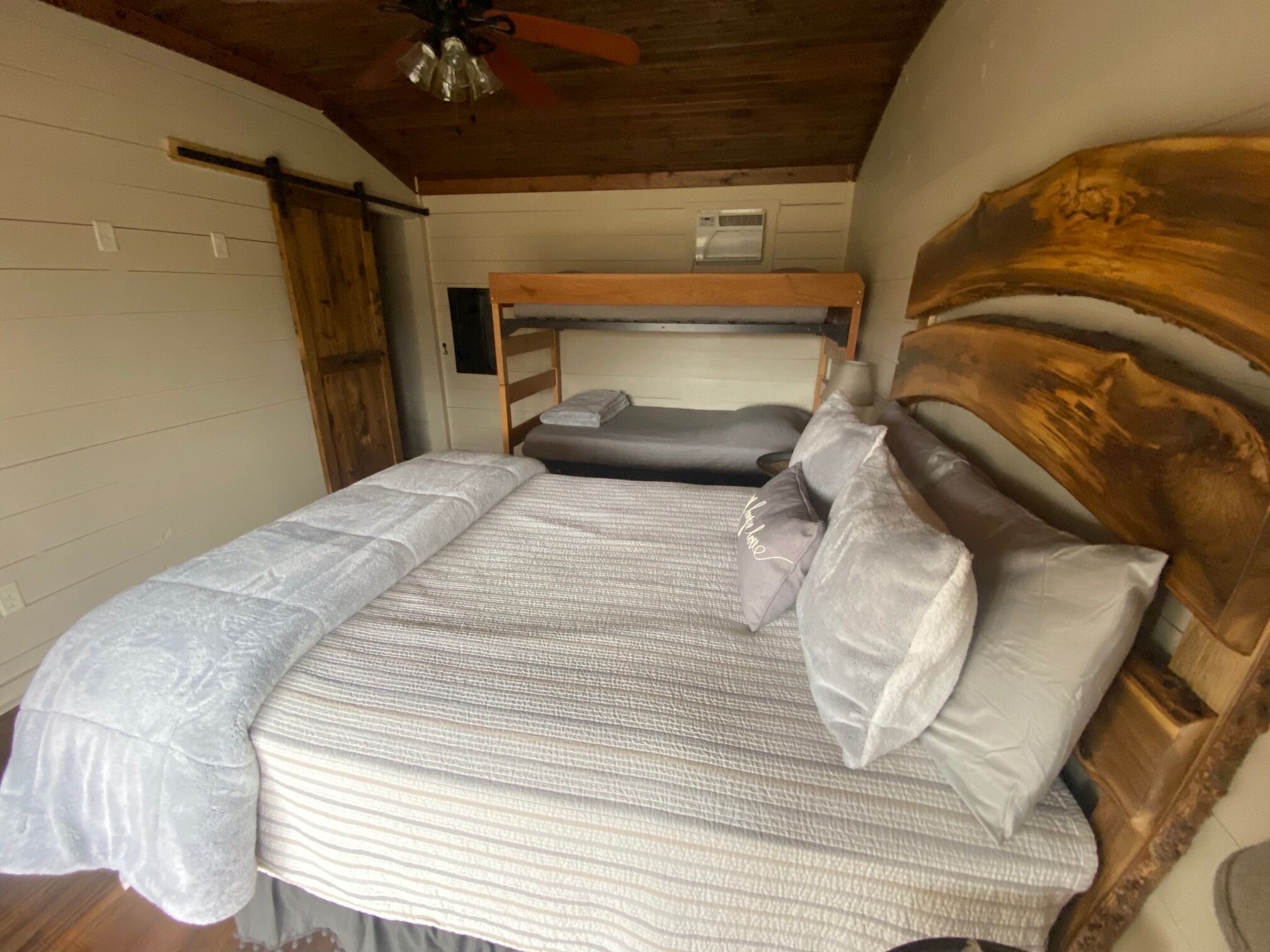 A bedroom with two beds, wooden headboards, and a ceiling fan.