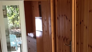 Un intérieur en bois avec une porte en verre donnant sur un balcon, une porte en bois et un couloir avec un réfrigérateur.