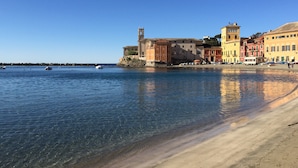 Une ville côtière avec des bâtiments le long du front de mer, une eau d’un bleu limpide et une plage de sable.