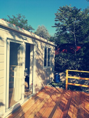 A small, single-story building with a wooden deck, a sliding glass door, and a small window. - Parco Vacanze Makallè (Sestri Levante)