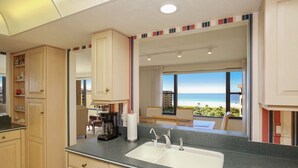 A modern kitchen with a large island, a double sink, and a view of the beach. - Gulf & Bay Club, TopFloor End Unit 1947sqft incl Lanai, (Siesta Key)