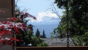 A view of a mountain range with snow-capped peaks in the distance, a body of water, and a building with a roof and a chain-link fence. - Authentic Mid-Century Marvel, in the quiet and desirable Mid Town neighborhood. (Bend)