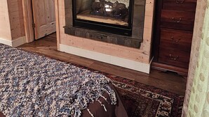A cozy room with a fireplace, a television mounted above it, and a patterned rug on the floor.