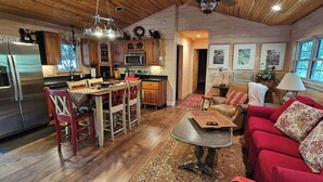 A cozy cabin interior with a kitchen, dining area, and living room. - Cabin Bascom - Walk to town, tankless hot water heater and new central HVAC!
(Highlands)