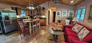 A cozy cabin interior with a kitchen, dining area, and living room. - Cabin Bascom - Walk to town, tankless hot water heater and new central HVAC!
(Highlands)