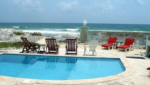 A pool with lounge chairs and a view of the ocean. - Casa Rosa -Beautiful Ocean Front Home - Studio Apartment (Isla Mujeres)