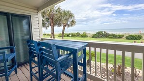 A covered outdoor area with a table and chairs, overlooking a beach with palm trees and a clear sky. - Direct Beachfront OFV D108 Private Beach 2BR 2BA (Myrtle Beach)