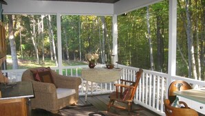 A covered porch with wicker furniture, a table, and chairs. - Lovely Cottage That Is Completely New With All The Luxuries You Would Want!   (Great Valley)