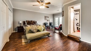 A spacious living room with hardwood flooring, a ceiling fan, a sofa, and a staircase leading to another room. - Beautiful Kayewood Waterfront Retreat (Little Elm)