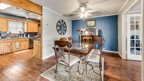 A dining area with a glass table, wooden chairs, and a ceiling fan. - Beautiful Kayewood Waterfront Retreat (Little Elm)