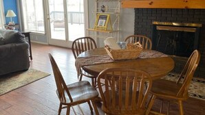 A cozy dining area with a wooden table and chairs, a fireplace, and a 'Be Our Guest' sign. - Beautiful Kayewood Waterfront Retreat (Little Elm)