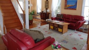 A living room with a red sofa, a wooden coffee table, and a staircase. - Gorgeous Designer Contemporary Beach House with Views (Clinton)