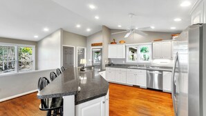 A modern kitchen with white cabinets, stainless steel appliances, and a granite countertop. - Caesar's Head Mountain Home ~ Sleeps 13 ~ Table Rock & Blue Ridge Views (Cleveland)