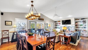 A spacious living area with a wooden dining table, comfortable seating, a fireplace, and a television. - Caesar's Head Mountain Home ~ Sleeps 13 ~ Table Rock & Blue Ridge Views (Cleveland)