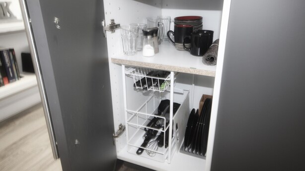 Un armario de cocina con estantes que contienen tazas, vasos y utensilios de cocina.