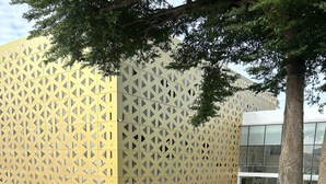 Un patio moderno al aire libre con piscina, sillas de descanso y un diseño de pared geométrico.