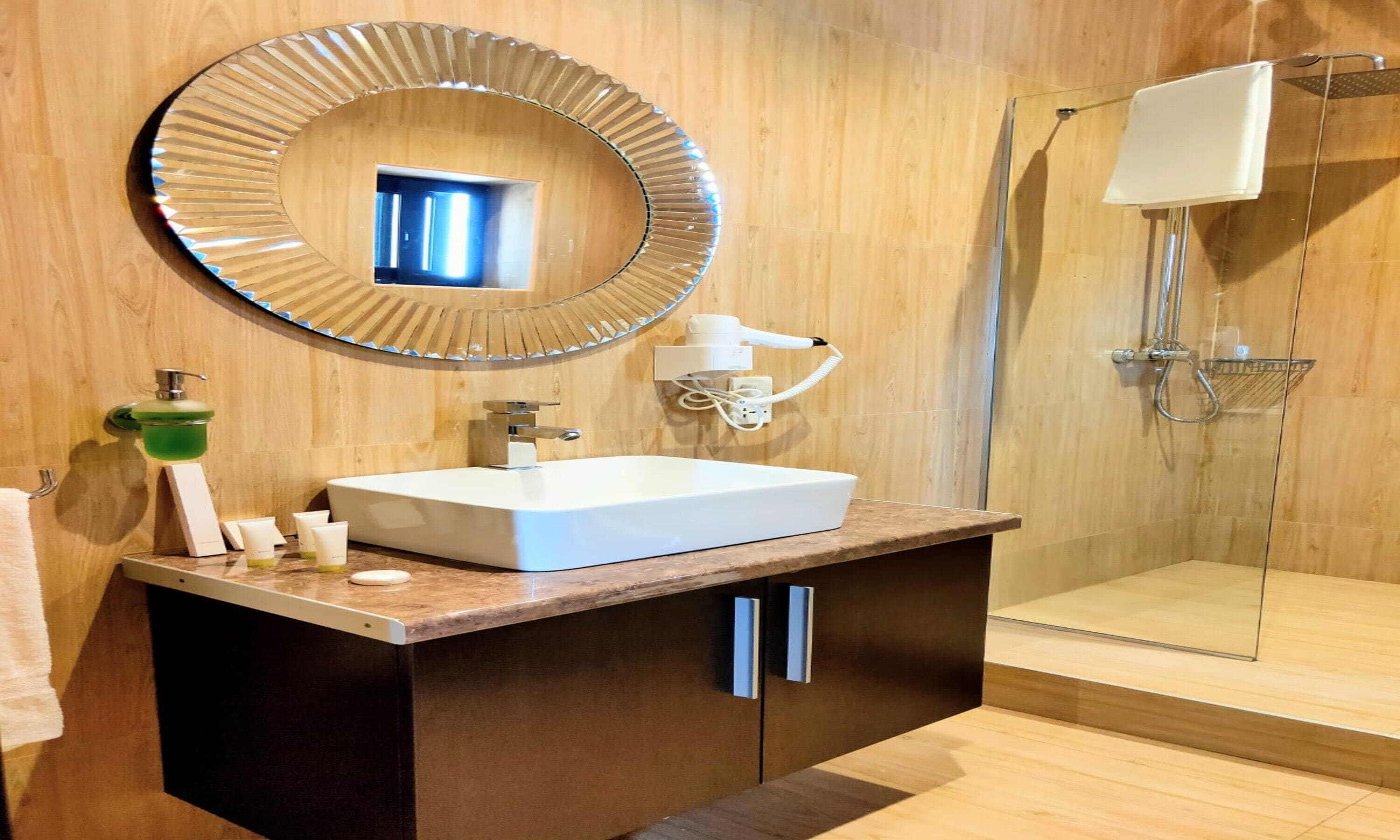 Un baño moderno con un espejo grande, un lavamanos y una ducha.