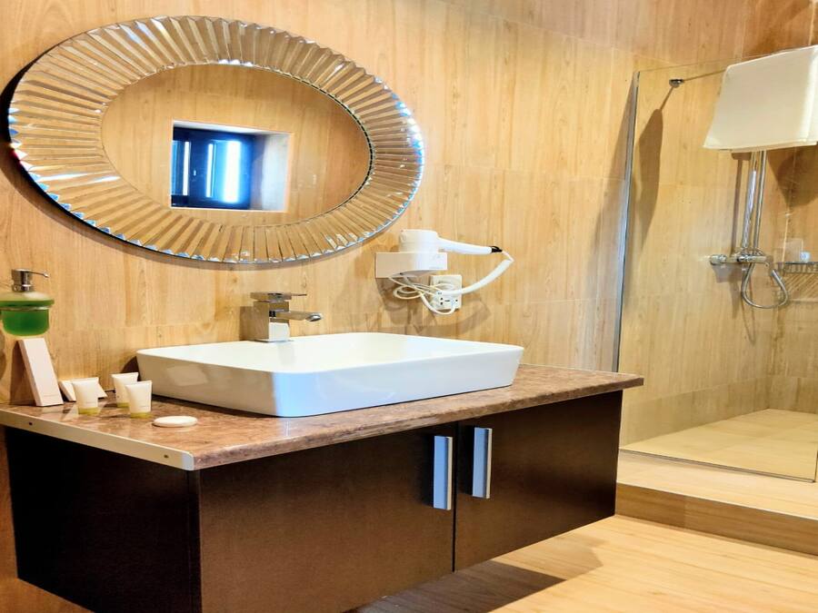 A modern bathroom with a large mirror, a sink, and a shower.