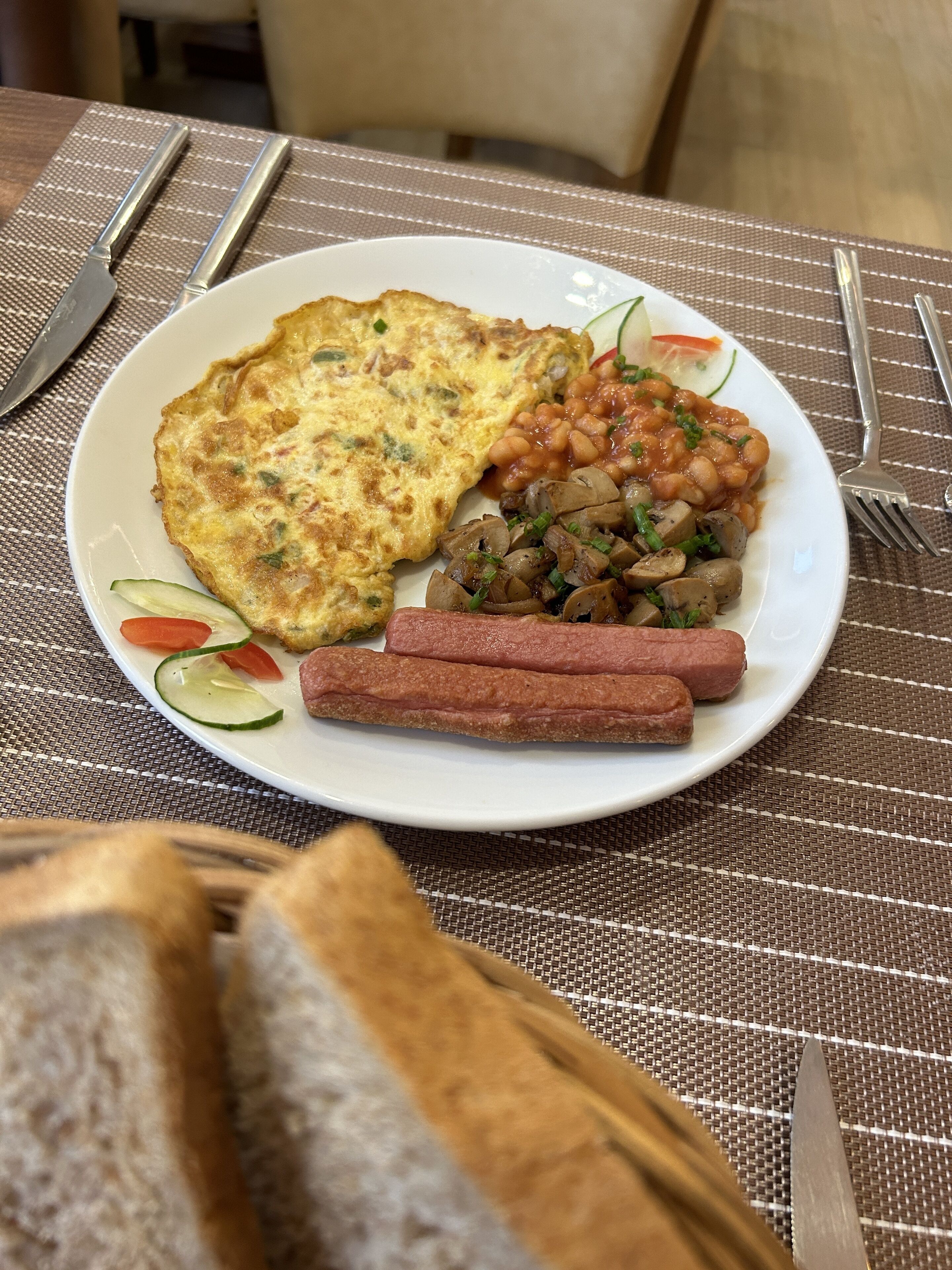 Un plato de comida con una tortilla, frijoles, champiñones y salchichas.