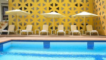 Una piscina techada, sombrillas, sillones reclinables de piscina