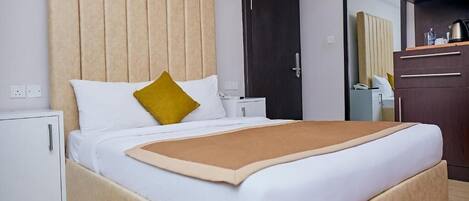 Una habitación de hotel con una cama, una mesita de noche, un armario y una puerta.