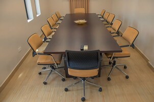 A conference room with a long table, multiple chairs, and a remote control on the table.