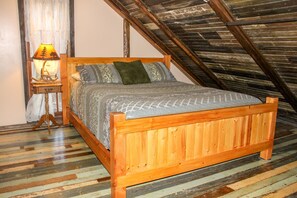 A wooden bed in a room with a sloped ceiling and a patterned floor.